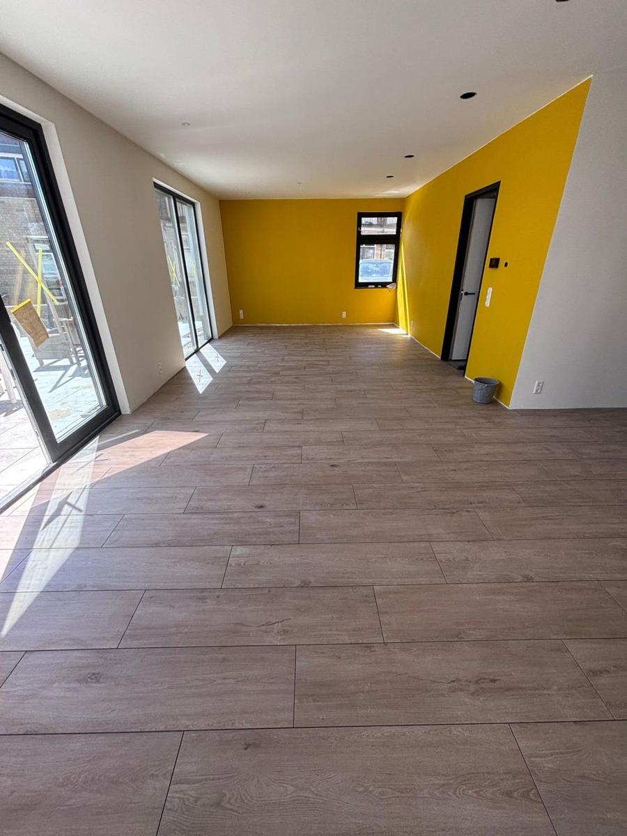 Woonkamer met houtlook vloertegels en gele wand